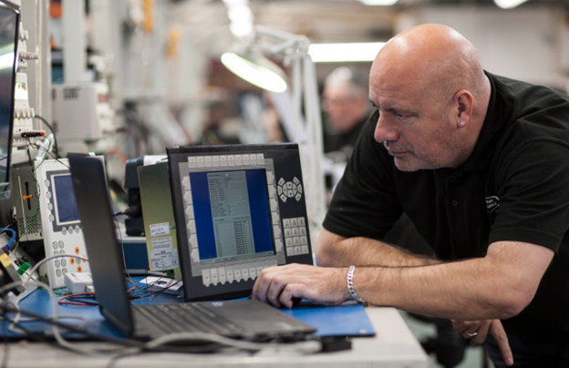 Technician diagnosing HMI panel at industrial workstation